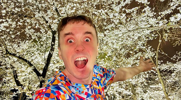 Marco Togni si scatta un selfie davanti ai fiori di ciliegio illuminati presso il teamLab Botanical Garden Osaka.