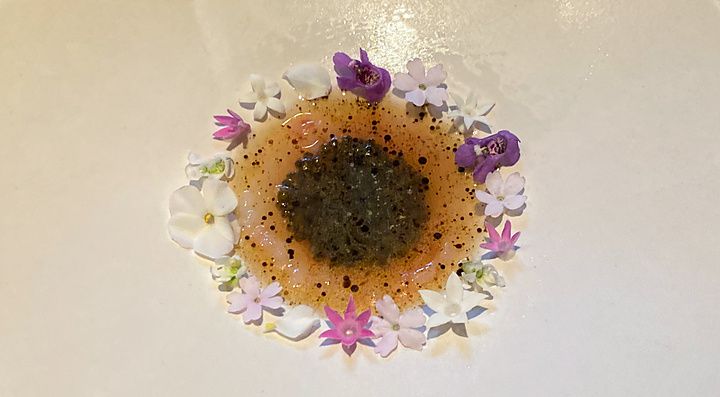 Un piatto di gambero e caviale di pomodoro presentato al Ristorante Crony, Tokyo, decorato con piccoli fiori colorati.