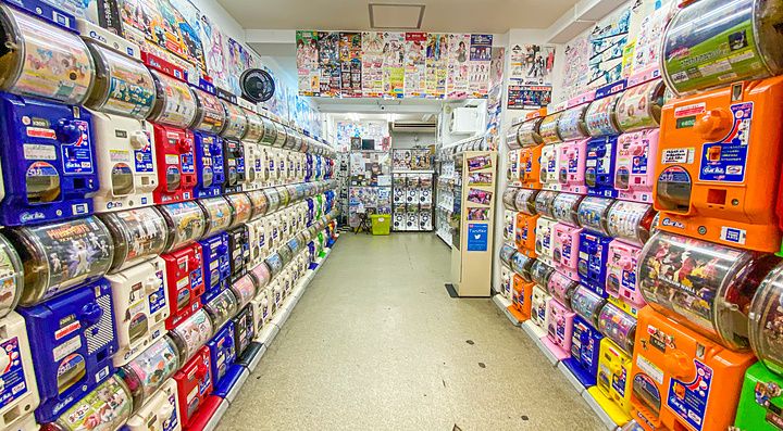Corridoio fiancheggiato da numerose macchinette gashapon colorate su entrambi i lati in un negozio ad Akihabara.