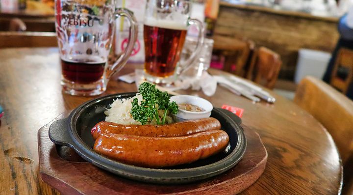 Salsicce grigliate con crauti in un piatto di ghisa su un tavolo di legno presso la birreria Ginza Lion.