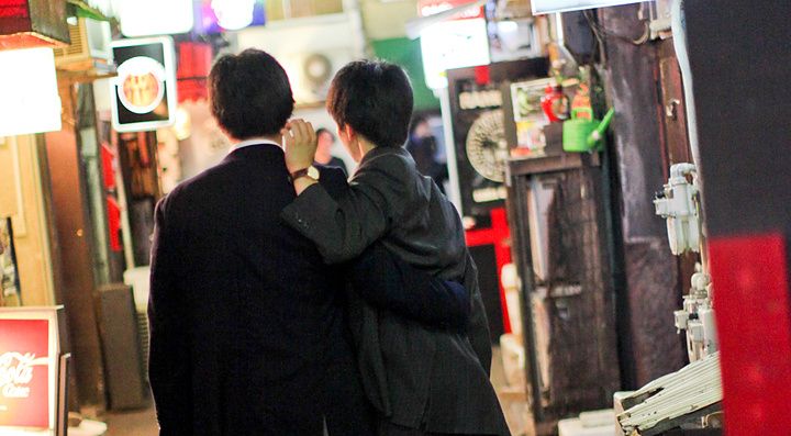 Due uomini camminano in un vicolo illuminato da insegne al neon a Golden Gai, Tokyo.