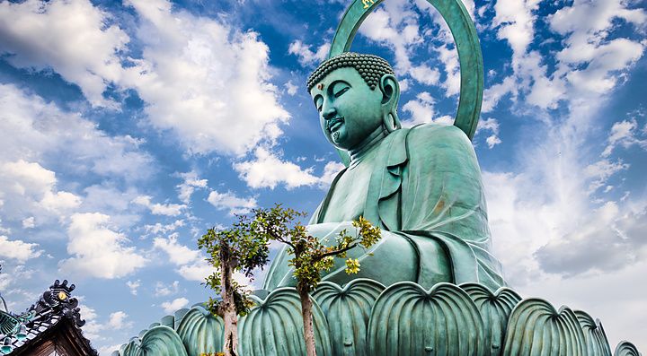 Grande Buddha di Takaoka sotto un cielo azzurro e nuvoloso.