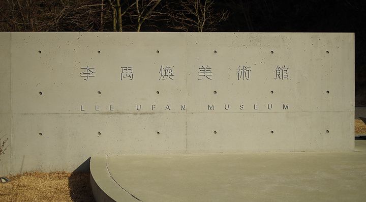 Parete in cemento a vista con scritte incise del Lee Ufan Museum in un'area esterna in Giappone.