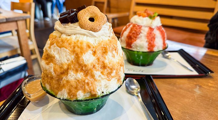 Due ciotole di kakigori con miso d'orzo e pesce servite su vassoi neri all'interno del locale Kanna a Tokyo.
