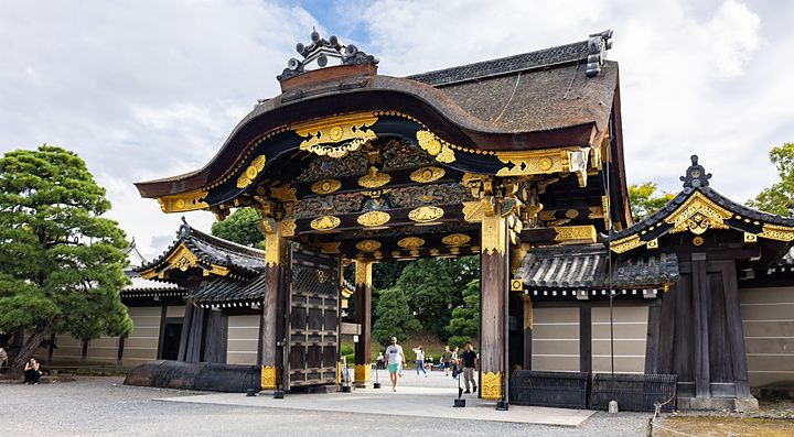 Veduta del Karamon Gate del castello di Nijo a Kyoto con tetti curvi e decorazioni dorate in una giornata parzialmente nuv...