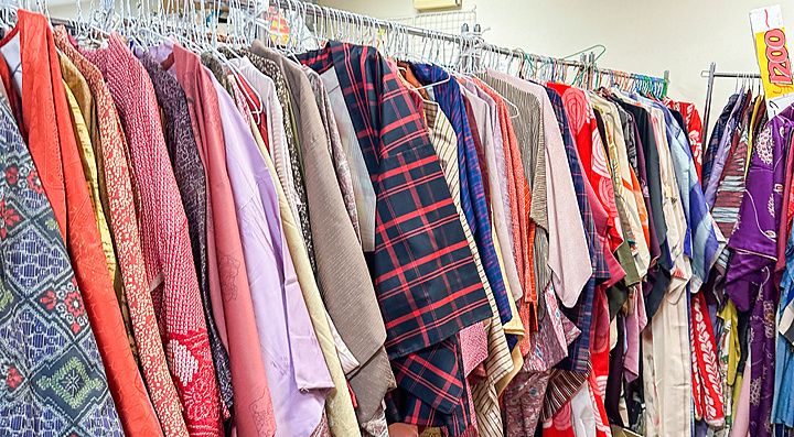 Una vasta selezione di kimono appesi a uno stand metallico all'interno di un negozio in Giappone.