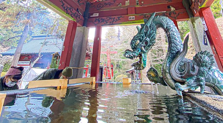 Fontana in bronzo a forma di drago presso il santuario Kitaguchi Hongu Fuji Sengen con persone che compiono la purificazione.
