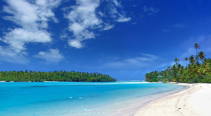 Splendida laguna tropicale con sabbia bianca e palme sotto un cielo azzurro.
