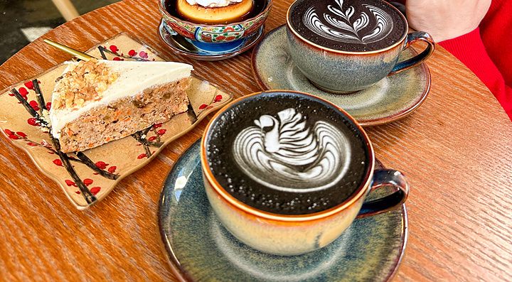 Marco Togni sorride accanto a caffè e dolci su un tavolo circolare presso il Liwei Coffee Stand, Tokyo.