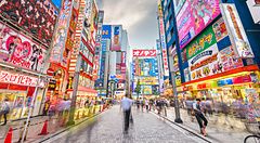 Street di Akihabara a Tokyo, con insegne colorate e folla in movimento.