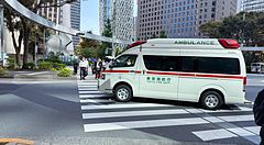 Ambulanza attraversa un incrocio a Shinjuku, Tokyo, tra grattacieli moderni.