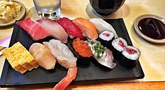 Assortimento di sushi con zuppa di miso su un tavolo di legno chiaro.