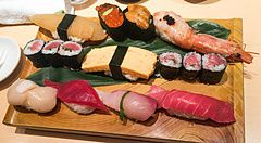 Vassoio di legno con assortimento di sushi, tra cui nigiri e hosomaki, servito al ristorante Sushi no Midori.