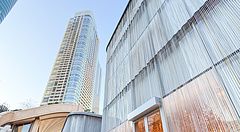 Boutique di lusso con facciata a fili metallici presso Azabudai Hills a Tokyo, con grattacieli sullo sfondo.
