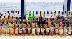 Bottiglie di whisky allineate sul bancone del bar nella lobby al Mitsui Garden Hotel Toyosu Premier con vista sulla baia.