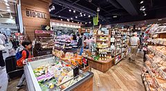 Interno del supermercato Bio-Ral con scaffalature in legno e clienti tra le corsie di prodotti biologici.