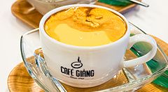 Due tazze di caffè all'uovo con il logo del Café Giang posate su vassoi di legno a Yokohama.