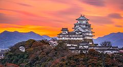 Castello di Himeji in Giappone all'alba con un cielo arancione e rosa.