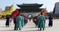 Cerimonia delle guardie reali al Gyeongbokgung Palace a Seoul con bandiere colorate.