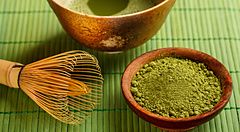 Ciotola di matcha e strumenti per la cerimonia del tè giapponese su tovaglietta verde.