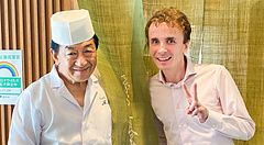 Uno scatto di Marco Togni insieme allo chef in divisa davanti alla tenda noren presso il ristorante Tempura Kondo.