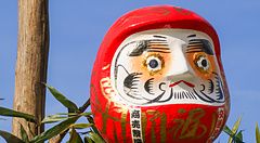 Due bambole Daruma rosse fissate su pali di legno durante il rituale del Dondoyaki in Giappone.