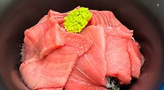 Una ciotola nera contenente fette di tonno crudo e wasabi su una base di riso servita presso Maguro Koya a Nara.