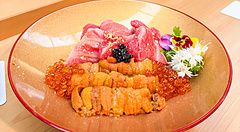 Un donburi premium con ikura, riccio di mare, chutoro e otoro servito su un piatto dorato presso il ristorante Waunn.