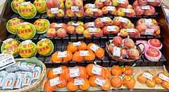 Banco di frutta confezionata in un supermercato giapponese con meloni, mele e arance.