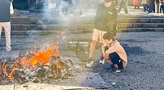 Persone attorno a un fuoco durante l'hatsumode al Santuario Kitaguchihongu Fuji Sengenjinja.