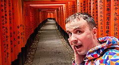 Marco Togni in giacca colorata tra i torii di Fushimi Inari a Kyoto.