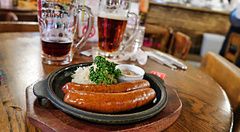 Salsicce grigliate con crauti in un piatto di ghisa su un tavolo di legno presso la birreria Ginza Lion.