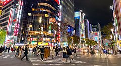 Strada affollata di notte a Ginza con luci al neon e cartelloni.