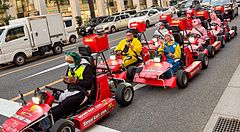 Persone su go-kart rosso in una strada di Tokyo.