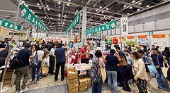 Interno della Good Life Fair a Tokyo con numerosi stand espositivi, visitatori e insegne in giapponese nel padiglione.