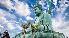 Grande Buddha di Takaoka sotto un cielo azzurro e nuvoloso.