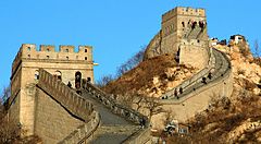 Parte della Grande Muraglia Cinese con torri e persone in cammino.