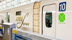 Un treno Shinkansen N700 Supreme bianco con il simbolo della Green Car e il numero 10 su una banchina ferroviaria.