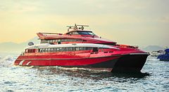 Traghetto rosso nel porto di Hong Kong al tramonto.