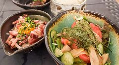 Insalata di umibudo e yukhoe di carne serviti in ciotole di ceramica su un tavolo da Izakaya Ichitaka a Iriomote.