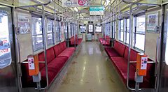 Interno di un treno giapponese con sedili rossi e appigli a soffitto vuoti