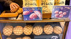 Vetrina in legno del negozio Kagetsudo ad Asakusa piena di melonpan e buste di carta gialla con scritte.