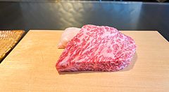 Un pezzo di manzo crudo finemente marezzato su un tagliere di legno chiaro al ristorante Kobe Beef Ishida, Ginza.