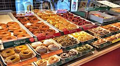 Espositore di ciambelle assortite all'interno di un negozio Krispy Kreme a Tokyo con una persona visibile.