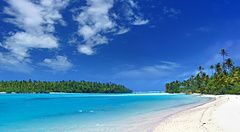 Splendida laguna tropicale con sabbia bianca e palme sotto un cielo azzurro.