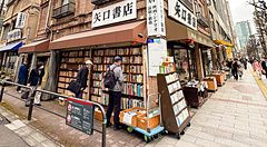 Libreria con libri antichi a Jimbocho, Tokyo, con persone sul marciapiede.