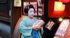 una maiko vestita in kimono cammina in un quartiere tradizionale di Kyoto.