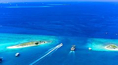 Mare azzurro tra Hulhumale e Hulhule alle Maldive con barche e isole.