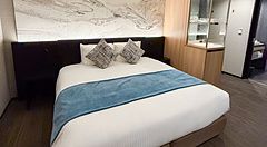 Stanza a Mitsui Garden Hotel Toyosu Premier con letto matrimoniale, testiera decorata e mobili in legno.