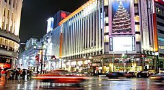 Mitsukoshi Ginza a Tokyo di notte sotto la pioggia con taxi e persone.